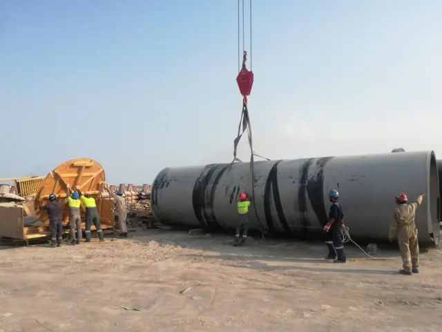 Site crew rigging a large fabricated HDPE spool for a crane lift in Kuwait