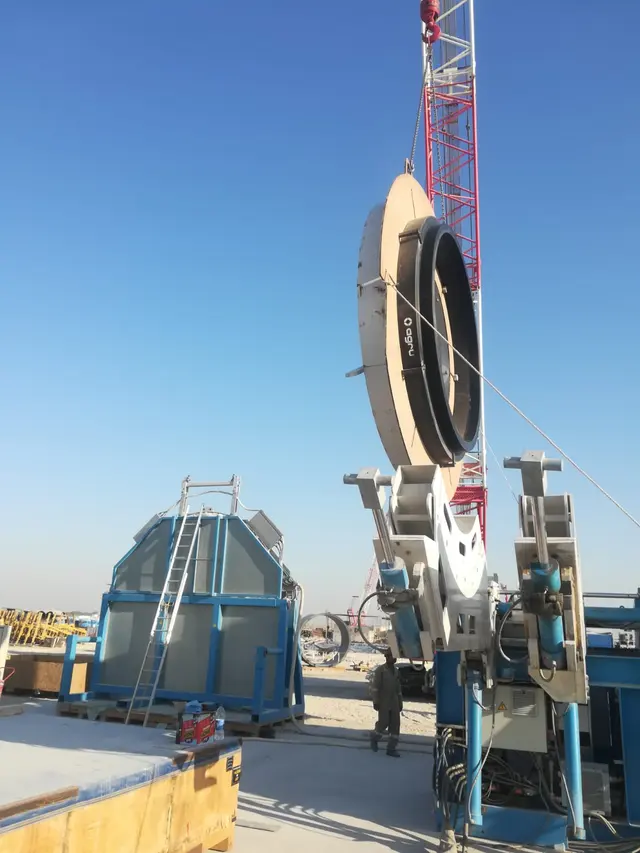 Large-diameter HDPE pipe lifted into a butt-fusion welding rig by crane in Kuwait