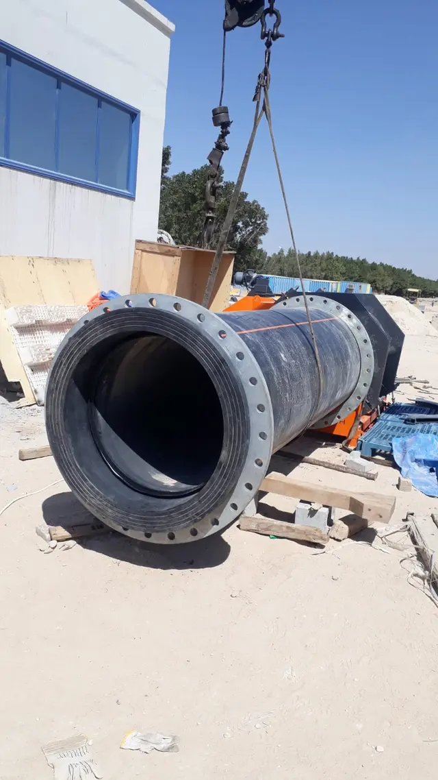 Crane lifting a flanged large-diameter HDPE pipe spool outside a Kuwait pump station