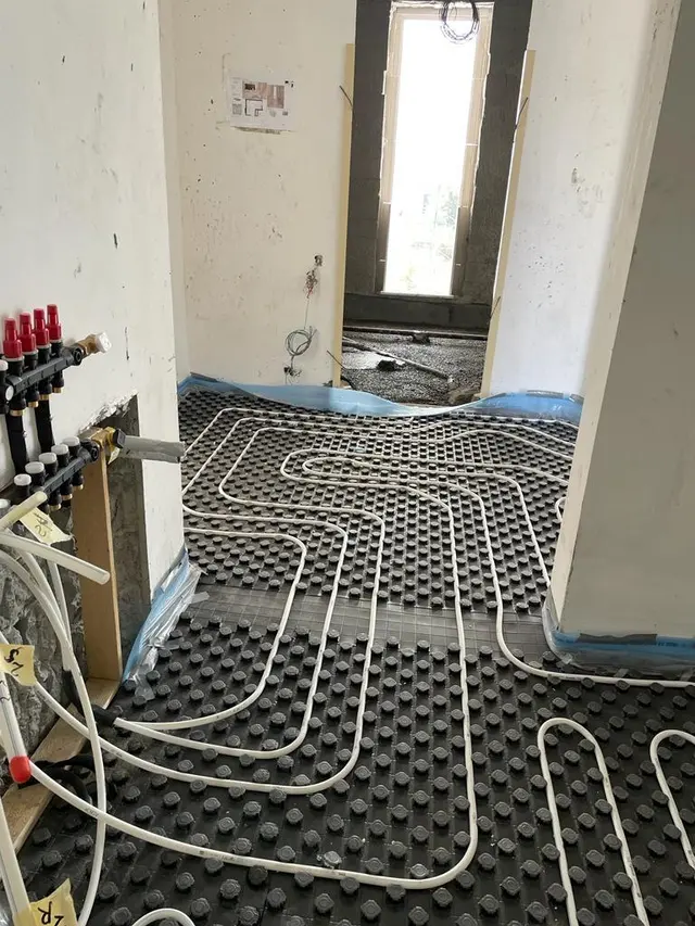 PEX underfloor heating loops laid over insulation panels with a manifold in a Kuwait villa