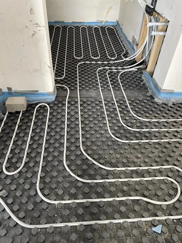 PEX underfloor heating pipe circuits clipped to studded insulation panels in Kuwait