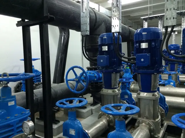 Plant-room pumps and valves below HDPE pipe carried on supports in Kuwait