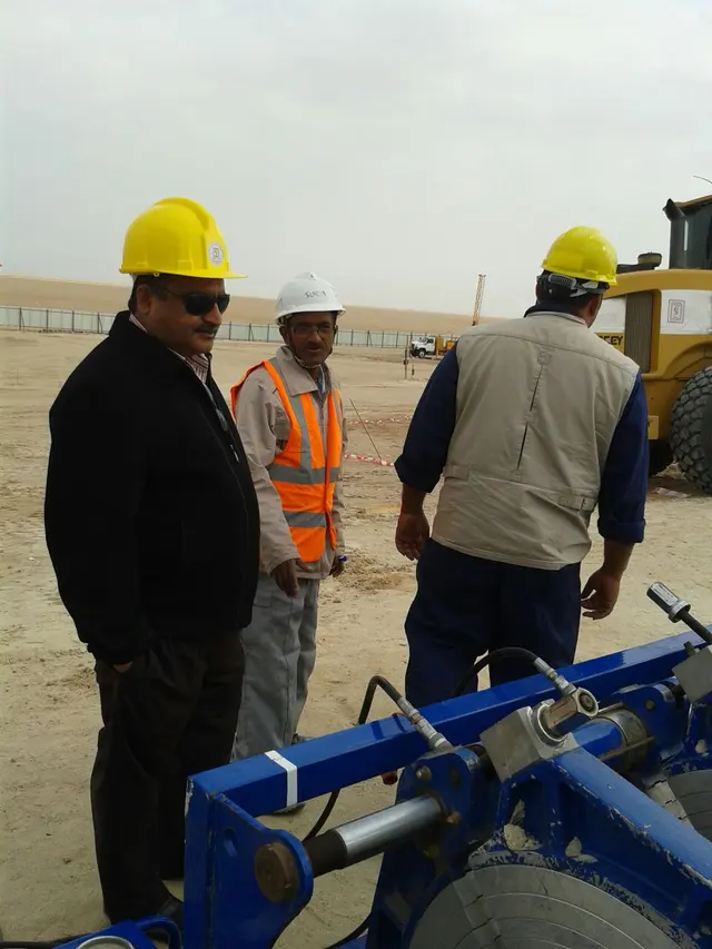 Site team around an HDPE butt-fusion rig with a wheel loader in Kuwait