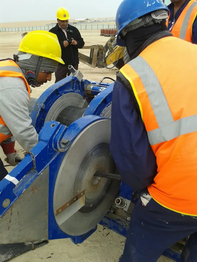 Workers facing an HDPE pipe end in a butt-fusion machine on a Kuwait site