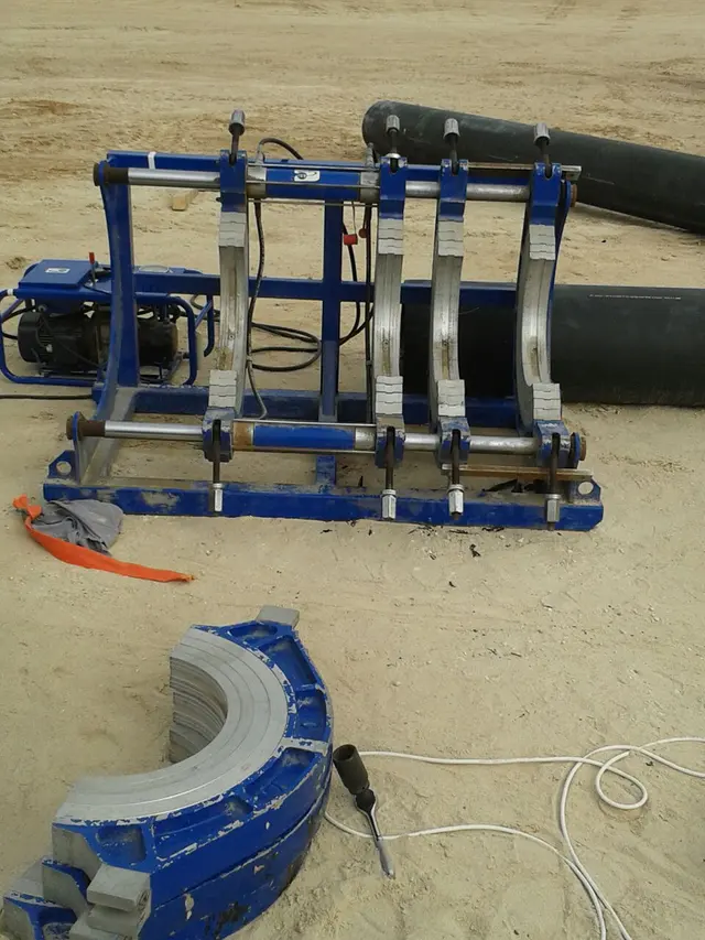 HDPE butt-fusion machine frame and heating plate beside pipe on a Kuwait site