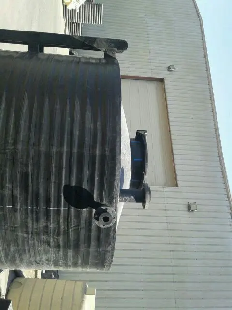 Large HDPE chemical storage tank with flanged nozzles beside a building in Kuwait